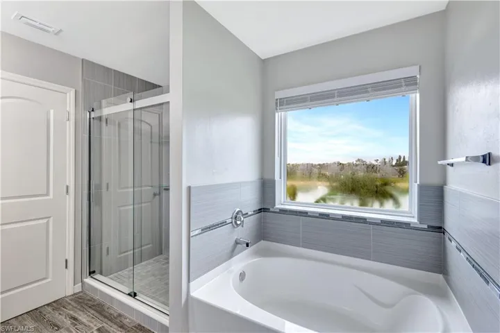Bathroom with a garden tub, a stall shower, and wood finished floors