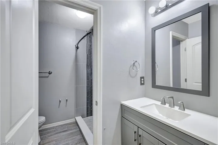Full bath featuring vanity, a shower stall, and wood finish floors