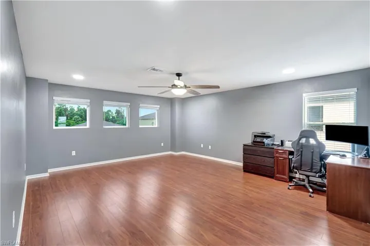Home office featuring light wood-style floors, healthy amount of natural light, a ceiling fan, and recessed lighting