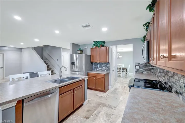 Kitchen with brown cabinets, appliances with stainless steel finishes, tasteful backsplash, light countertops, and recessed lighting