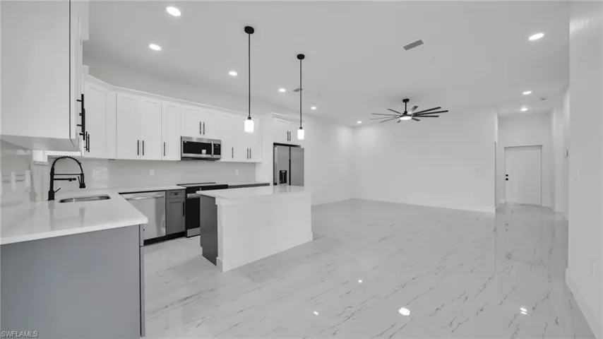 Kitchen with a kitchen island, stainless steel appliances, pendant lighting, a ceiling fan, and open floor plan