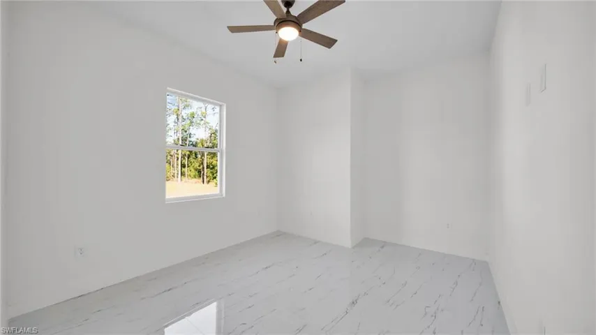 Unfurnished room featuring light marble finish flooring and ceiling fan