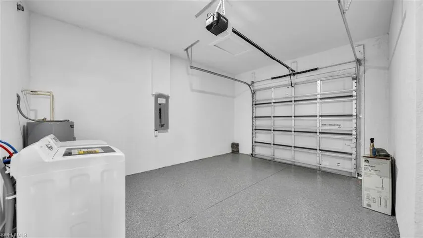 Garage with independent washer and dryer, a garage door opener, electric panel, and water heater