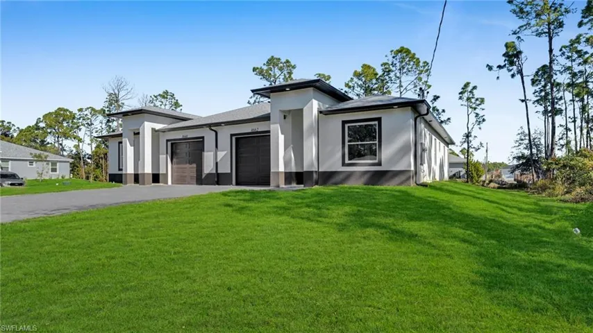 Prairie-style home with a garage, a front yard, asphalt driveway, and stucco siding
