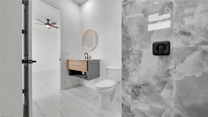 Full bathroom featuring vanity, a ceiling fan, and light marble finish floors