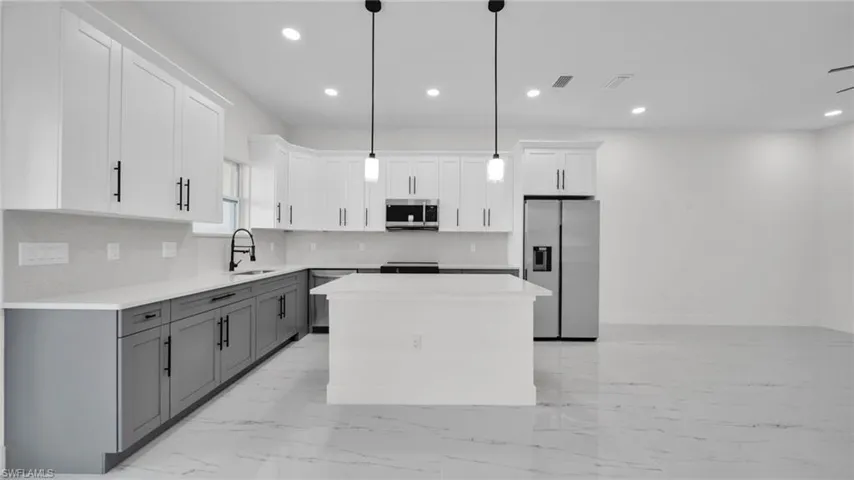 Dual tone kitchen with a kitchen island, stainless steel appliances, backsplash, two tone color scheme, and pendant lighting