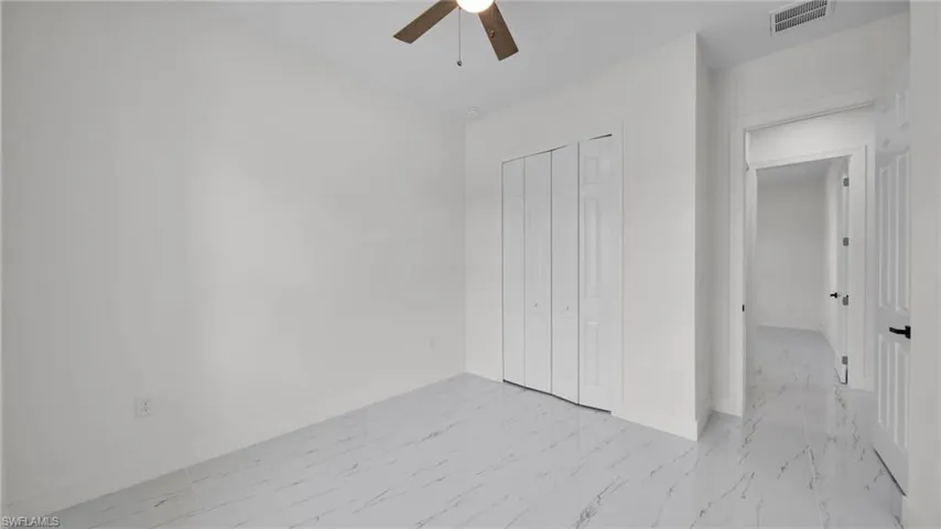 Unfurnished bedroom with light marble finish floors, a closet, and a ceiling fan