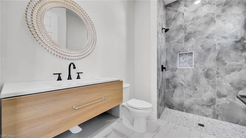 Full bathroom with a marble finish shower, vanity, and marble look tiles