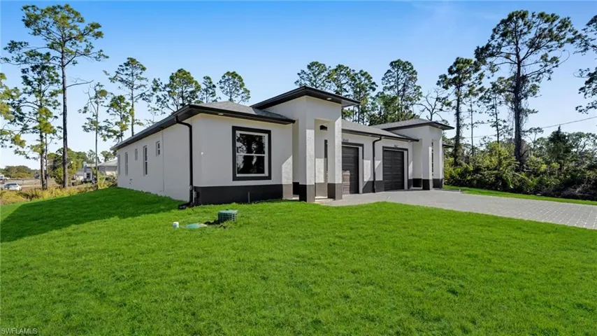 View of front of house featuring stucco siding, a front yard, decorative driveway, and an attached garage