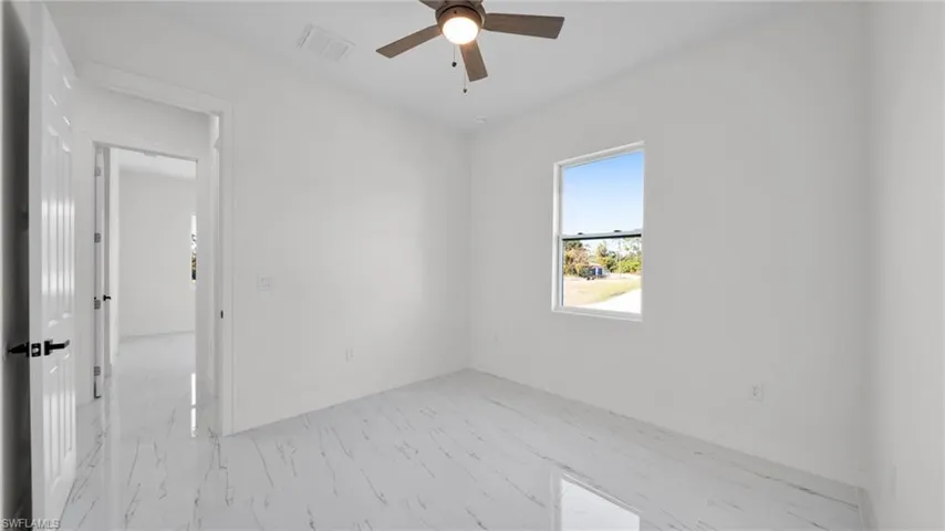 Unfurnished room featuring a ceiling fan and light marble finish flooring