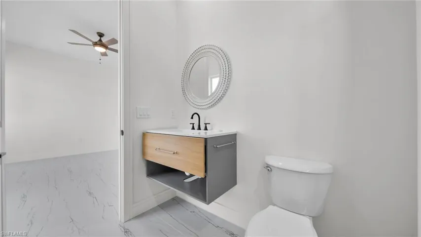 Bathroom featuring vanity, a ceiling fan, and light marble finish flooring