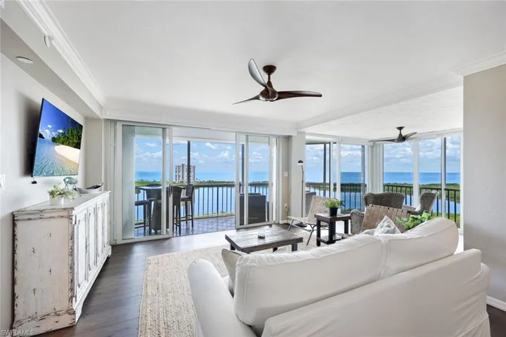 Living room featuring dark hardwood / wood-style floors, a water view, crown molding, and ceiling fan
