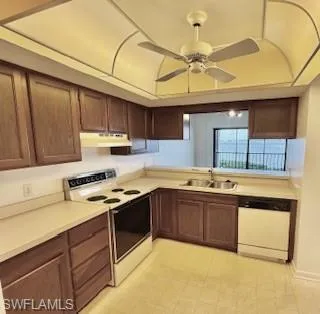 Kitchen featuring white appliances, light countertops, and under cabinet range hood