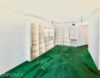Empty living room featuring carpet floors and track lighting