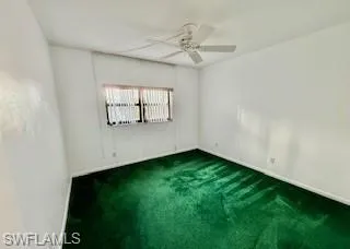 Guest bedroom featuring dark colored carpet and ceiling fan