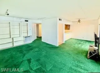 Unfurnished living room featuring carpet, rail lighting, and ceiling fan
