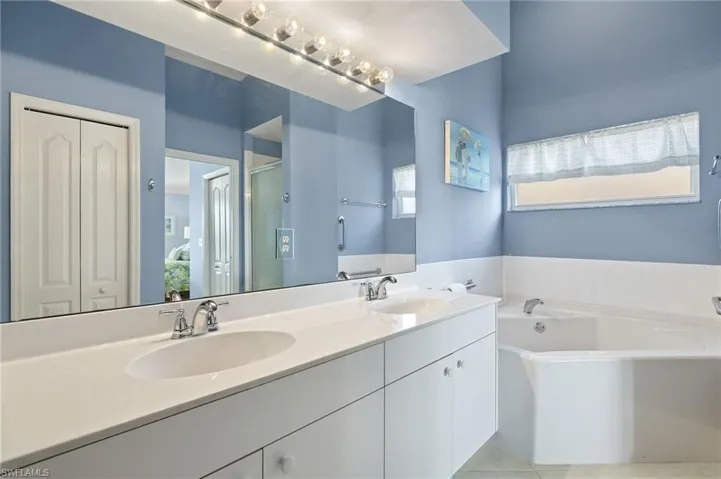 Full bath with a shower, double vanity, a garden tub and window providing natural light.