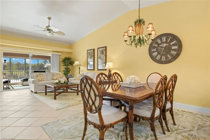 Dining area with light tile patterned flooring, crown molding, vaulted ceiling, and ceiling fan with notable chandelier