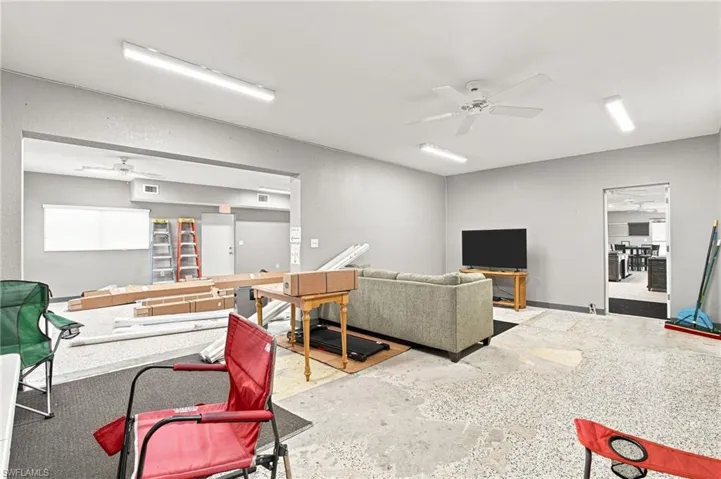 Concrete flooring with a speckled finish, ceiling fans, and fluorescent lighting