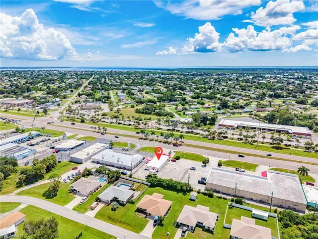 Aerial perspective showcasing a commercial building with a white exterior, a paved parking area, and a flat roof