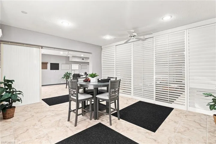 Recessed lighting, ceiling fan, large-format tile flooring, white louvered window treatments, and a sliding panel door