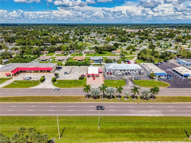 Commercial property with multiple buildings, paved parking areas, and mature palm trees