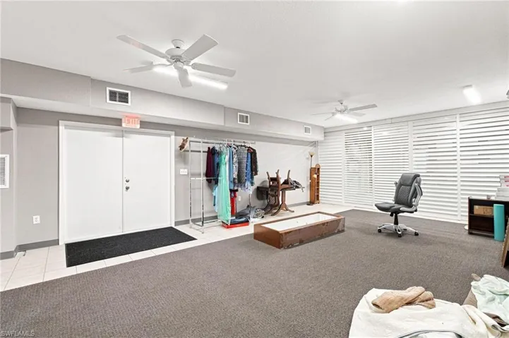 Interior space featuring dual ceiling fans, wall-to-wall carpeting, and white louvered window coverings