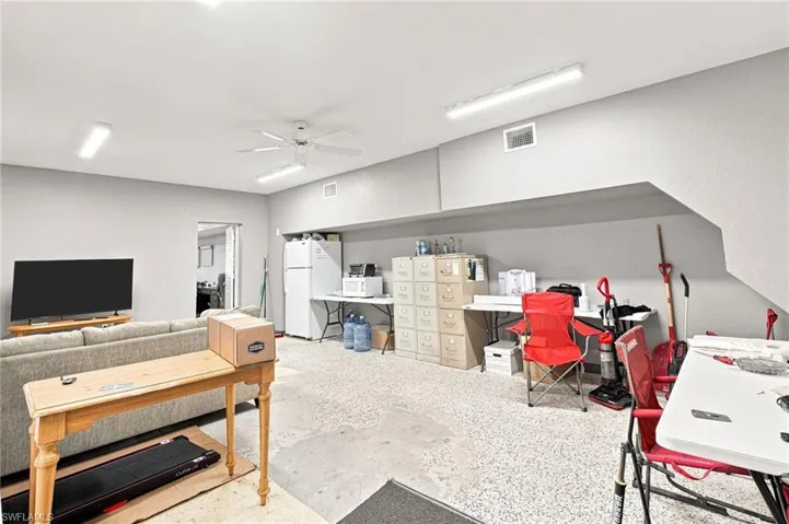 Recessed ceiling with multiple overhead light fixtures, ceiling fan, and concrete flooring