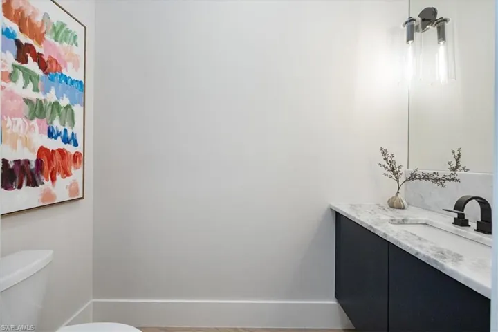 The powder bath is tucked away just off of the main living area with a slab front floating cabinet and dual sconces.