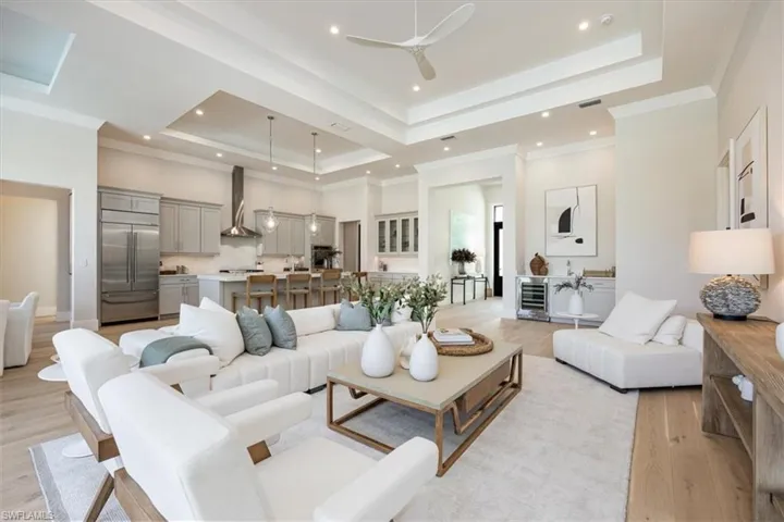 The open concept main living area features white oak flooring, 12-14' ceilings over the foyer, open chef's kitchen and wet bar, great room, and dining area.