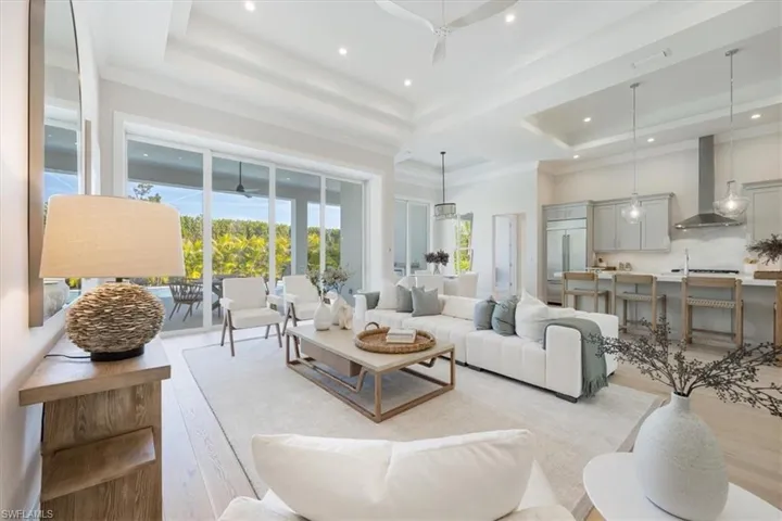 The open concept main living area features white oak flooring, 12-14' ceilings over the foyer, open chef's kitchen and wet bar, great room, and dining area.