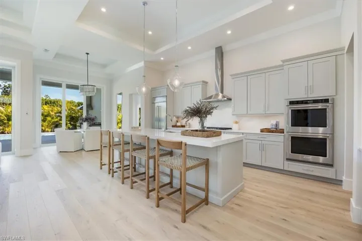 The kitchen features built-in KitchenAid french door refrigerator with freezer drawers, natural gas cooking, double ovens, and dishwasher in the island. Soft sand colored cabinetry and Pompeii quartz countertops and full backsplash complete the fresh design.