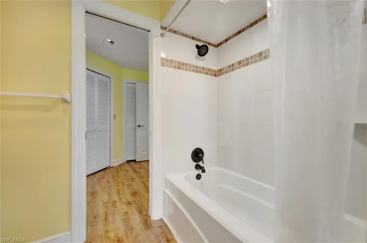 Full bath featuring shower / bath combination with curtain, light wood-type flooring, and a closet