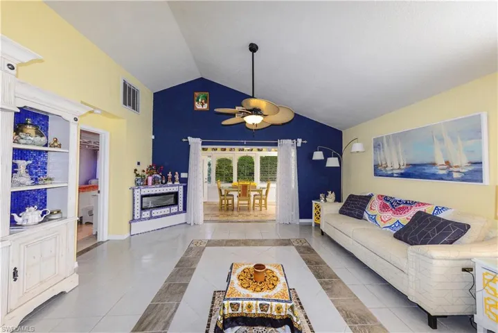 Sunroom dining area featuring vaulted ceilings, a ceiling fan, and tile flooring
