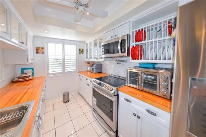 Kitchen featuring a stainless steel double basin sink, light wood-finish countertops, and white paneled cabinetry with dark hardware
