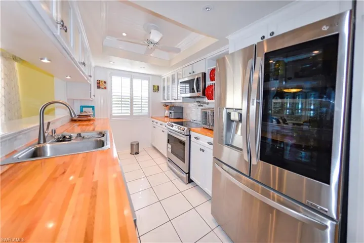 Kitchen featuring white cabinetry, wood-finish countertops, and a dual-basin sink