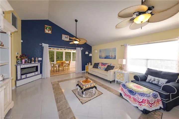 Living area featuring vaulted ceilings, patterned tile flooring, and multiple ceiling fans