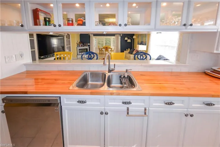 Modern kitchen featuring white cabinetry, stainless steel appliances, marble-look backsplash, wood-finish countertops, and recessed lighting