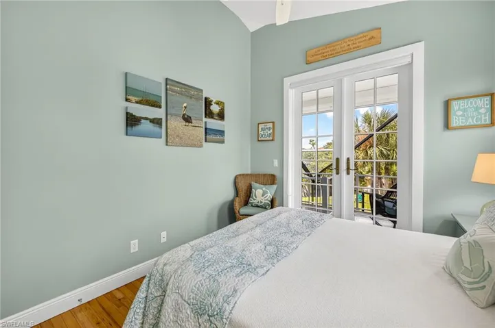 Bedroom with access to outside, french doors, wood finished floors, and vaulted ceiling