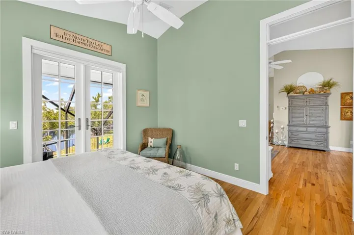 Bedroom with access to exterior, vaulted ceiling, wood finished floors, french doors, and ceiling fan