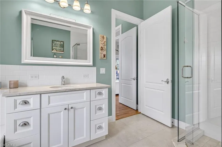 Bathroom featuring vanity, a shower stall, tile patterned flooring, and backsplash