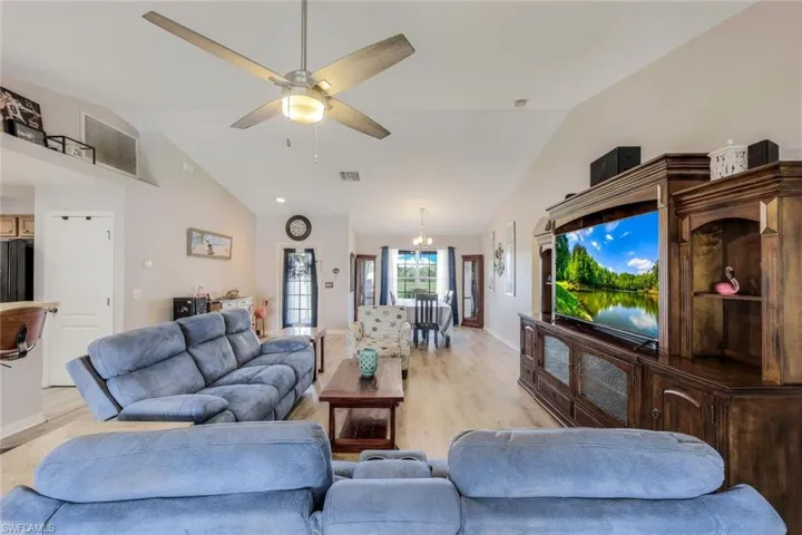 Living room featuring lofted ceiling, ceiling fan, and light wood-type flooring