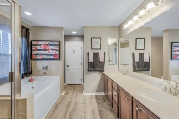 Bathroom with hardwood / wood-style flooring, a bath, and double vanity