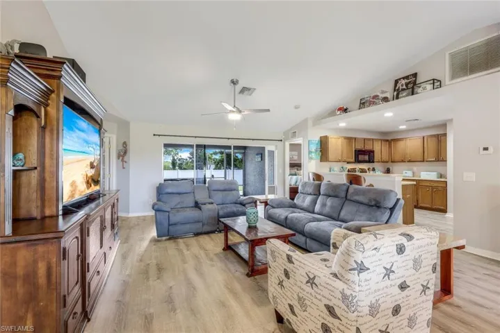 Living room with vaulted ceiling, light wood-type flooring, and ceiling fan