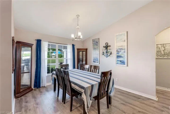 Dining room featuring vaulted ceiling, hardwood / wood-style floors, and a chandelier