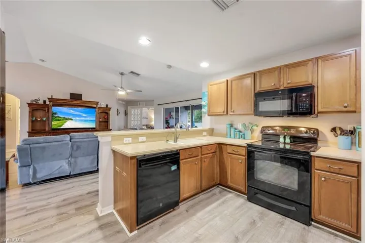 Kitchen with sink, kitchen peninsula, ceiling fan, and black appliances