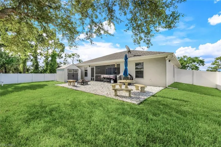Rear view of house with a patio area, a storage unit, and a lawn