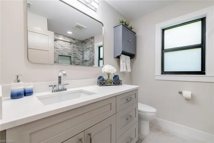 Bathroom featuring vanity, tiled shower, and light tile patterned floors