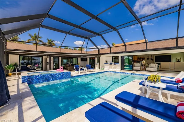 Integrated pool / spa with glass enclosure, a sunroom, and a patio