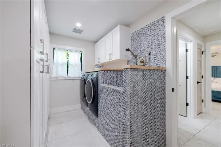 Laundry area with cabinet space, light tile patterned floors, and washer and dryer